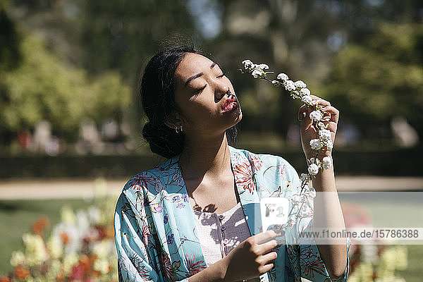 Beautiful young woman holding flower in a public garden in spring