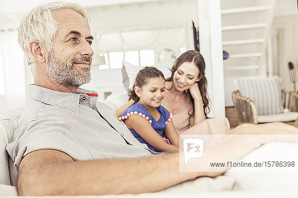 Smiling mature man with family on couch in living room