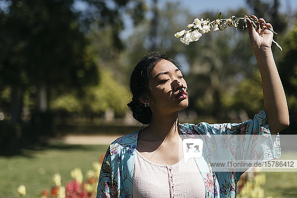 Beautiful young woman holding flower in a public garden in spring