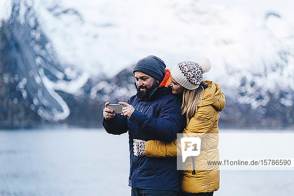 Touristenpaar mit Smartphone auf Hamnoy  Lofoten  Norwegen