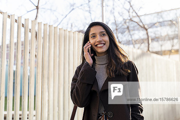 Smiling young woman on the phone in the city
