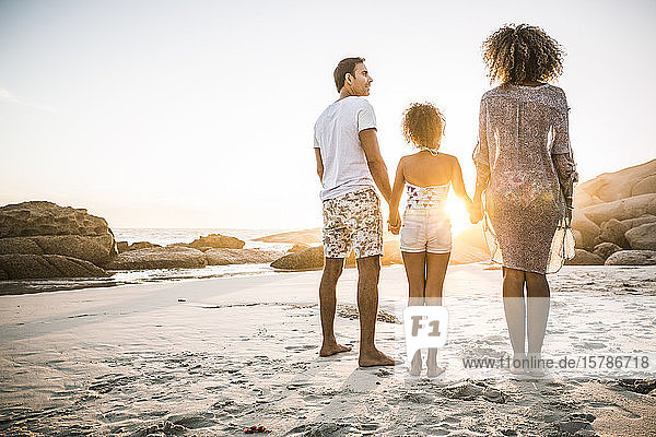 Familie genießt Sonnenuntergang am Strand