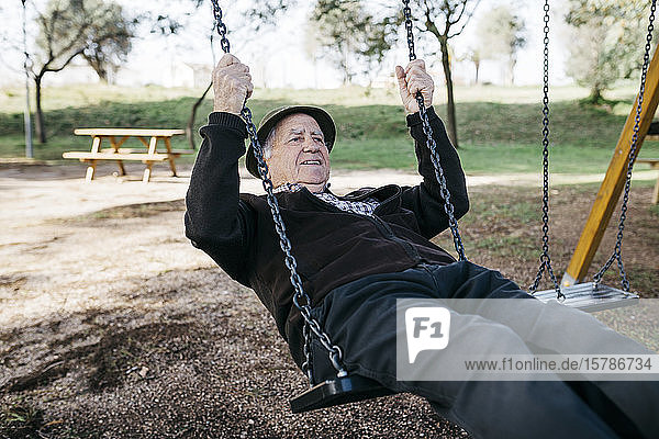 Alter Mann schaukelt auf Spielplatz im Park