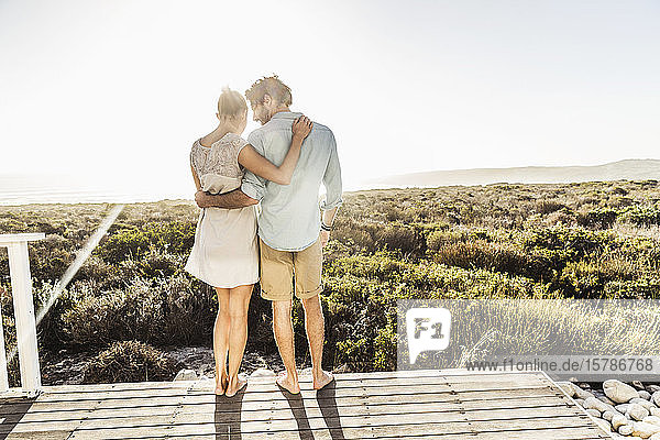 Affectionate young couple embracing on terrace at the coast in summer