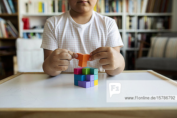 Crop view of little boy playing with building blocks at home