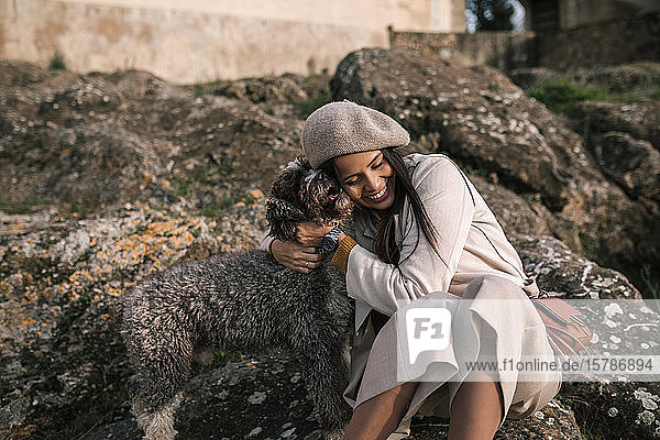Happy young woman cuddling her dog in the city