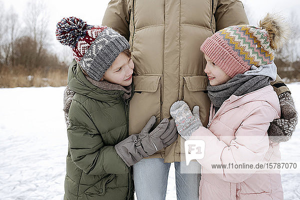 Zwei lächelnde Geschwister zusammen mit Vater im Winter