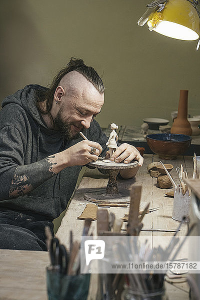 Potter working on a tiny figurine in workshop