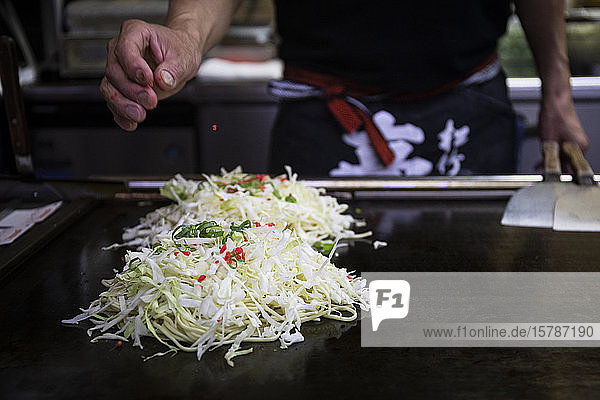 Japan  Kyoto  Nahaufnahme des Küchenchefs bei der Zubereitung von Okonomiyaki im Restaurant
