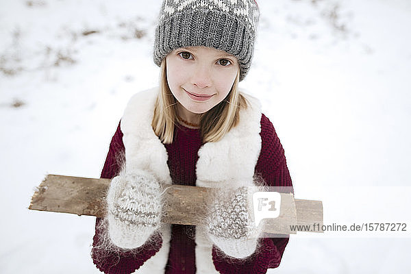 Porträt eines lächelnden Mädchens  das im Winter Brennholz trägt