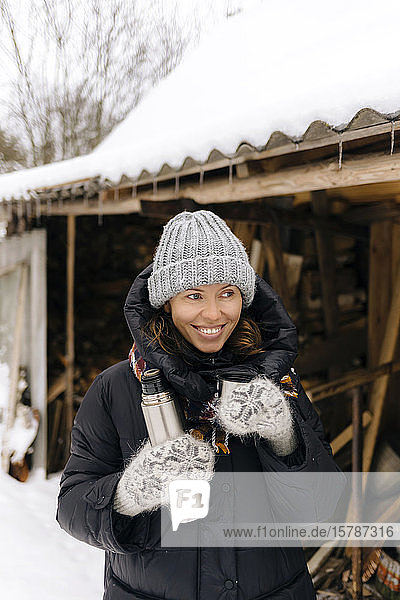 Portrait of happy woman with thermo flask in winter
