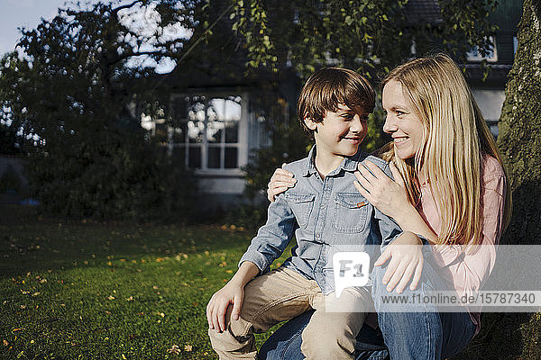 Mother and son crouching in garden  smiling
