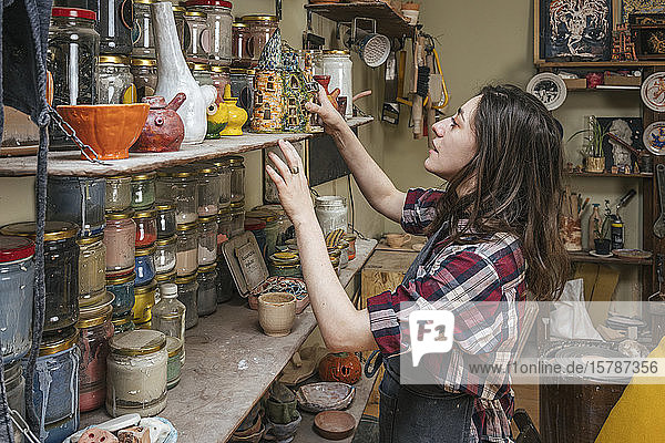 Potter at a shelf with products in workshop