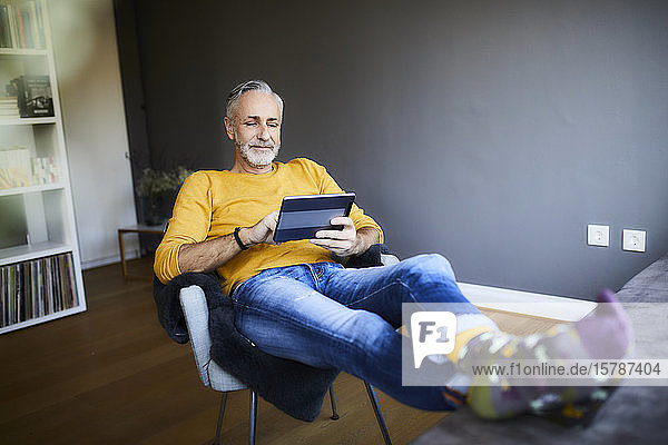 Relaxed mature man at home using tablet