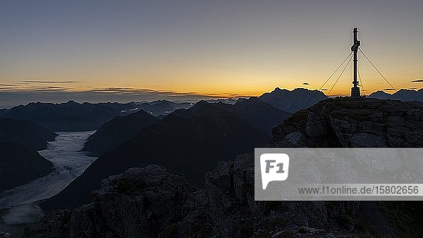 Sonnenaufgang mit Gipfelkreuz des Thanell und Lechtaler Alpen mit Nebel im Tal  Berwang  Lechtal  Außerfern  Tirol  Österreich  Europa