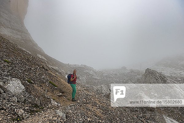 Young woman  hiking in a scree field in the fog in the mountains  bad visibility  circumnavigation of Sorapiss  Dolomites  Belluno  Italy  Europe