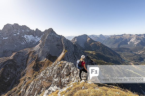 Junge Frau  Bergsteigerin mit Kletterhelm  Blick auf Berglandschaft  Wanderung zur Ehrwalder Sonnenspitze  hinter Grünstein und westlicher Marienbergspitze  Ehrwald  Mieminger Kette  Tirol  Österreich  Europa