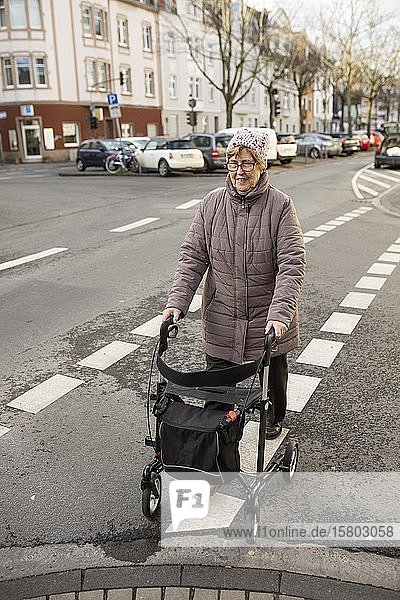 Senior citizen with rollator crosses a street in the city  Cologne  North Rhine-Westphalia  Germany  Europe