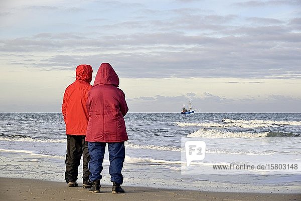 Two people on the beach watching a crab cutter off Norderney  North Sea  East Frisian Islands  Lower Saxony  Germany  Europe