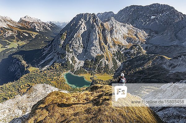 Young woman with climbing helmet looking at Seebensee from the Ehrwalder Sonnenspitze  left Leutaschtal  middle Vorderer and Hinterer Tajakopf  right Drachensee  Ehrwald  Mieminger Kette  Tyrol  Austria  Europe