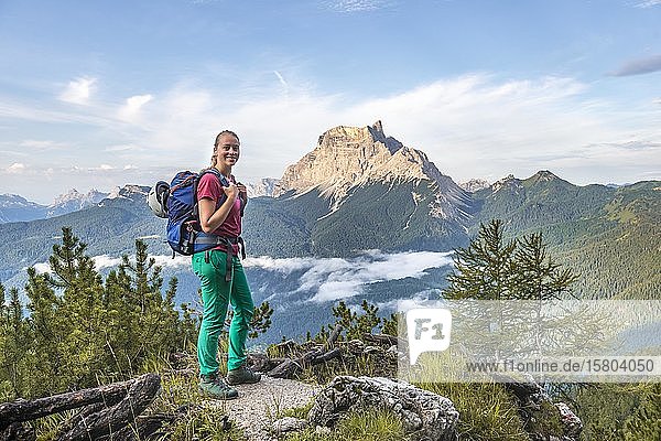Young female hiker looks into the camera  behind her mountain peak La Rocheta  Dolomites  Belluno  Italy  Europe