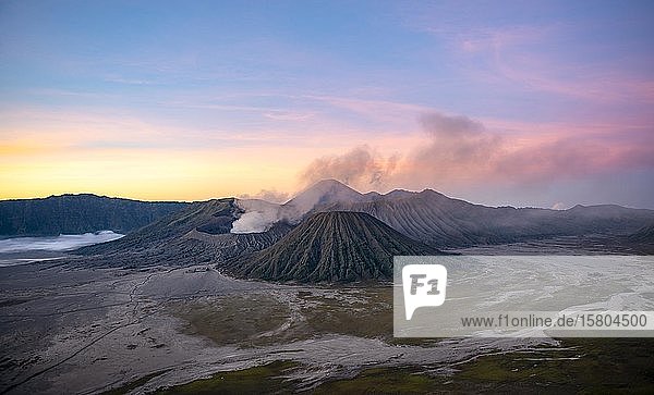 Volcanic landscape at sunrise  smoking volcano Gunung Bromo  with Mt. Batok  Mt. Kursi  Mt. Gunung Semeru  Bromo-Tengger-Semeru National Park  Java  Indonesia  Asia