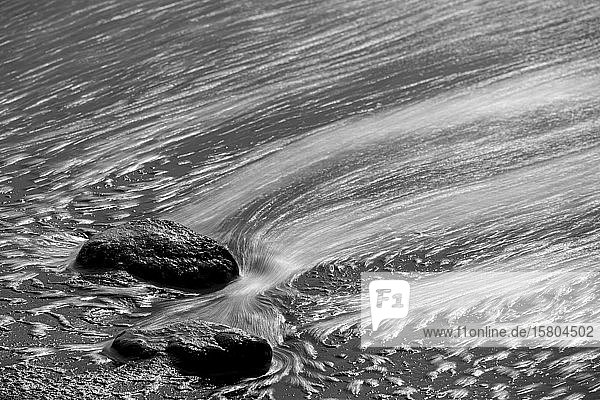 Mit Wasser umspülte Steine im schwarzen Lavasand schwarz-weiß La Palma Kanaren Spanien Europa
