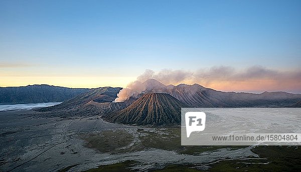 Volcanic landscape at sunrise  smoking volcano Gunung Bromo  with Mt. Batok  Mt. Kursi  Mt. Gunung Semeru  Bromo-Tengger-Semeru National Park  Java  Indonesia  Asia