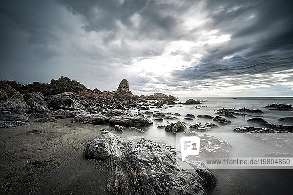Rocky coast  rocks on the beach  dark rain clouds  long time exposure  West Coast  South Island  New Zealand  Oceania