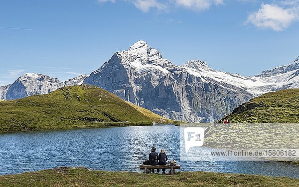 Hikers resting on a bench  Bachalpsee with summit Wetterhorn  Grindelwald  Bernese Oberland  Switzerland  Europe