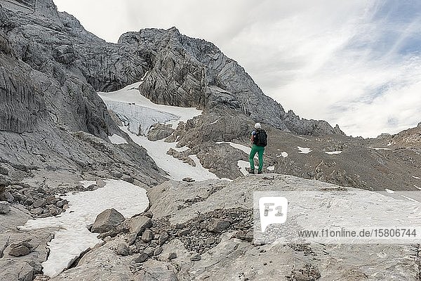 Hiker looks at alpine landscape  snow hole glacier  Niederes Kreuz  Dachstein  Salzkammergut  Upper Austria  Austria  Europe