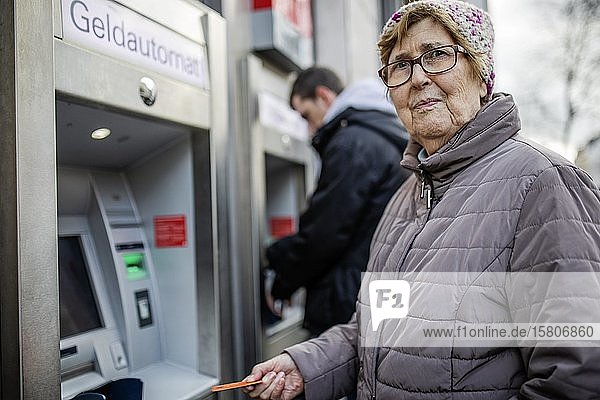 Seniorin mit Geldkarte am Geldautomaten schaut skeptisch  Köln  Nordrhein-Westfalen  Deutschland  Europa