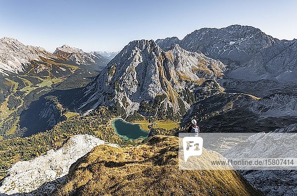 Young woman with climbing helmet looking at Seebensee from the Ehrwalder Sonnenspitze  left Leutaschtal  middle Vorderer and Hinterer Tajakopf  right Drachensee  Ehrwald  Mieminger Kette  Tyrol  Austria  Europe