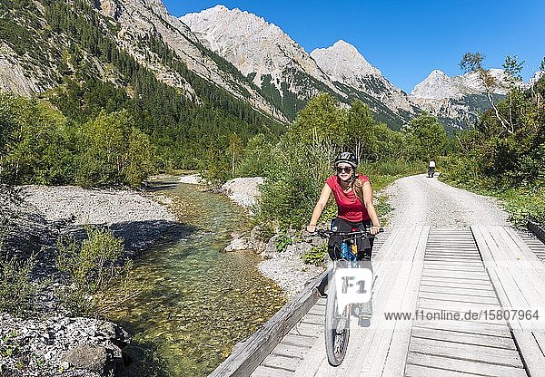 Cyclist  mountain biker bikes on bridge over mountain stream  gravel path to Karwendelhaus  Karwendeltal  Tyrol  Austria  Europe