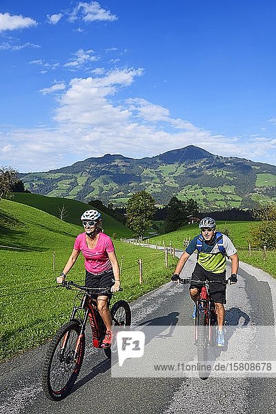 Two cyclists with electric mountain bikes on the Glantersberg with view of the Hohe Salve  Kitzbühel Alps  Tyrol  Austria  Europe