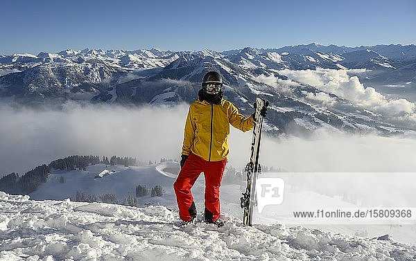 Skifahrer an der Skipiste stehend mit Ski in der Hand  Blick in die Ferne  Gipfel Hohe Salve  SkiWelt Wilder Kaiser Brixenthal  Hochbrixen  Tirol  Österreich  Europa
