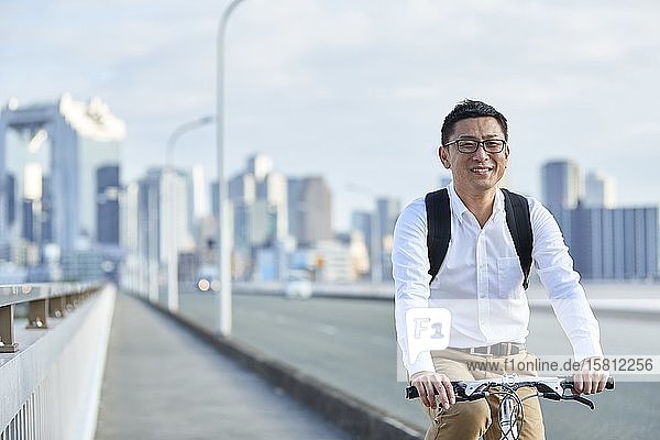 Mature Japanese man with bike downtown Osaka Japan