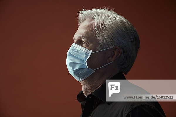 Grauhaariger Mann in Profilaufnahme mit Mundschutz