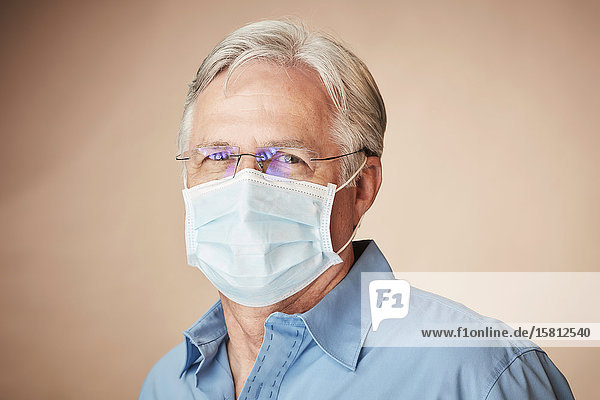 Grauhaariger Mann mit Mundschutz blickt in Kamera