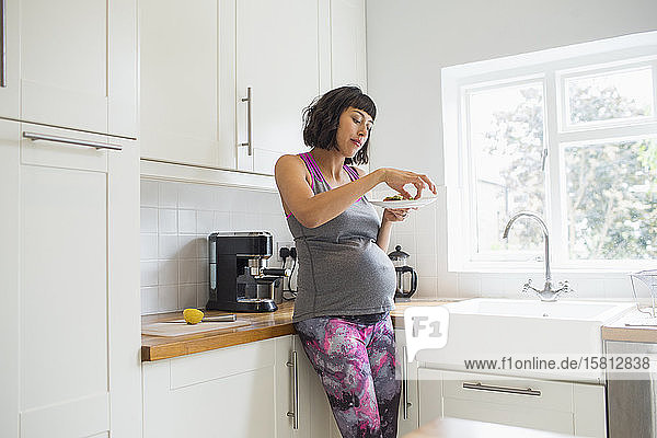 Schwangere Frau beim Essen in der Küche