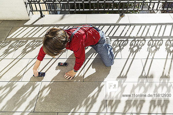 Ein sechsjähriger Junge spielt mit Spielzeugautos auf der Terrasse