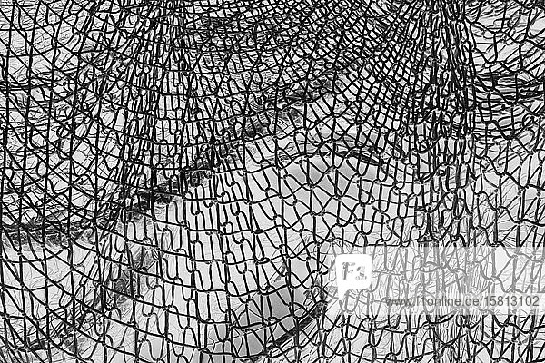 Umgekehrtes Schwarzweißbild kommerzieller Fischernetze und Seile auf einem Fischerkai.