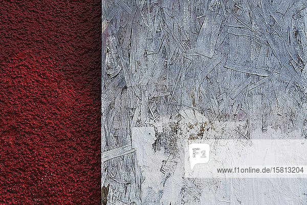 Painted white particle board against red stucco