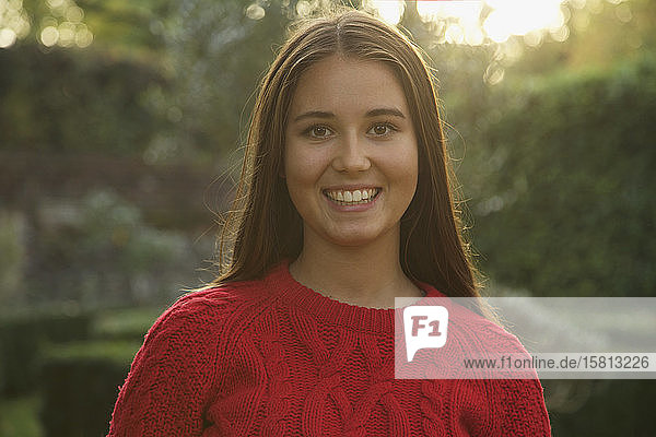 Porträt glückliches jugendliches Mädchen in rotem Pullover im Park