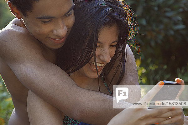 Zärtliches Teenager-Paar mit Smartphone