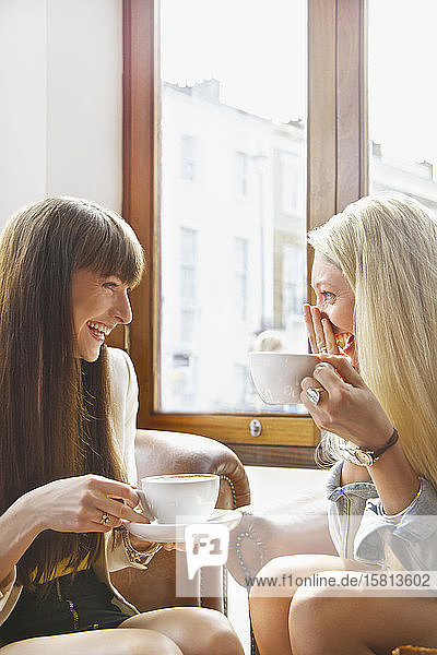 Glückliche junge Frauen trinken Kaffee in einem Caféfenster