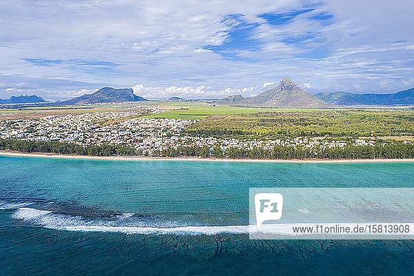 Aerial view by drone of waves crashing on Flic en Flac beach with Piton de la Petite Riviere Noire mountain Mauritius Indian Ocean Africa