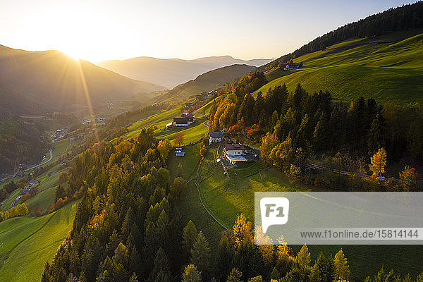 Sunbeam at sunset lighting the warm colors of autumn in Funes Valley aerial view Dolomites Bolzano province South Tyrol Italy Europe