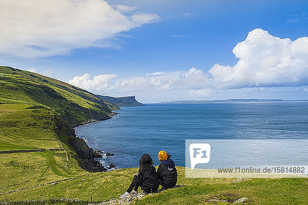 Two young hikers taking a rest on a walking trail along the Antrim coast  Ulster  Northern Ireland  United Kingdom  Europe