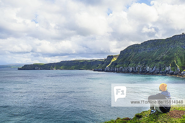 A young hiker taking a rest on a walking trail along the Antrim coast  Ulster  Northern Ireland  United Kingdom  Europe